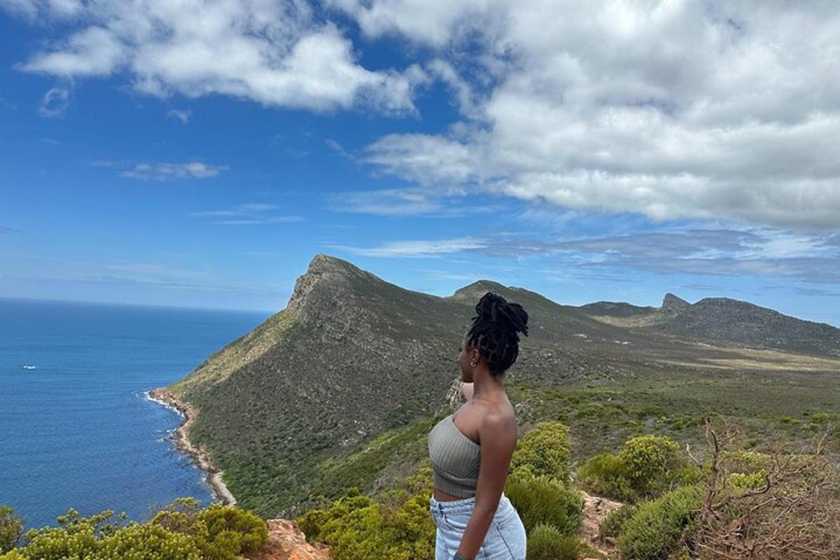 uma mulher em pé no topo de uma montanha com vista para o oceano
