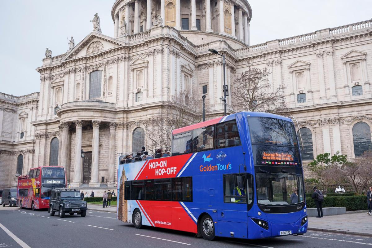 a blue double decker bus driving in front of a building
