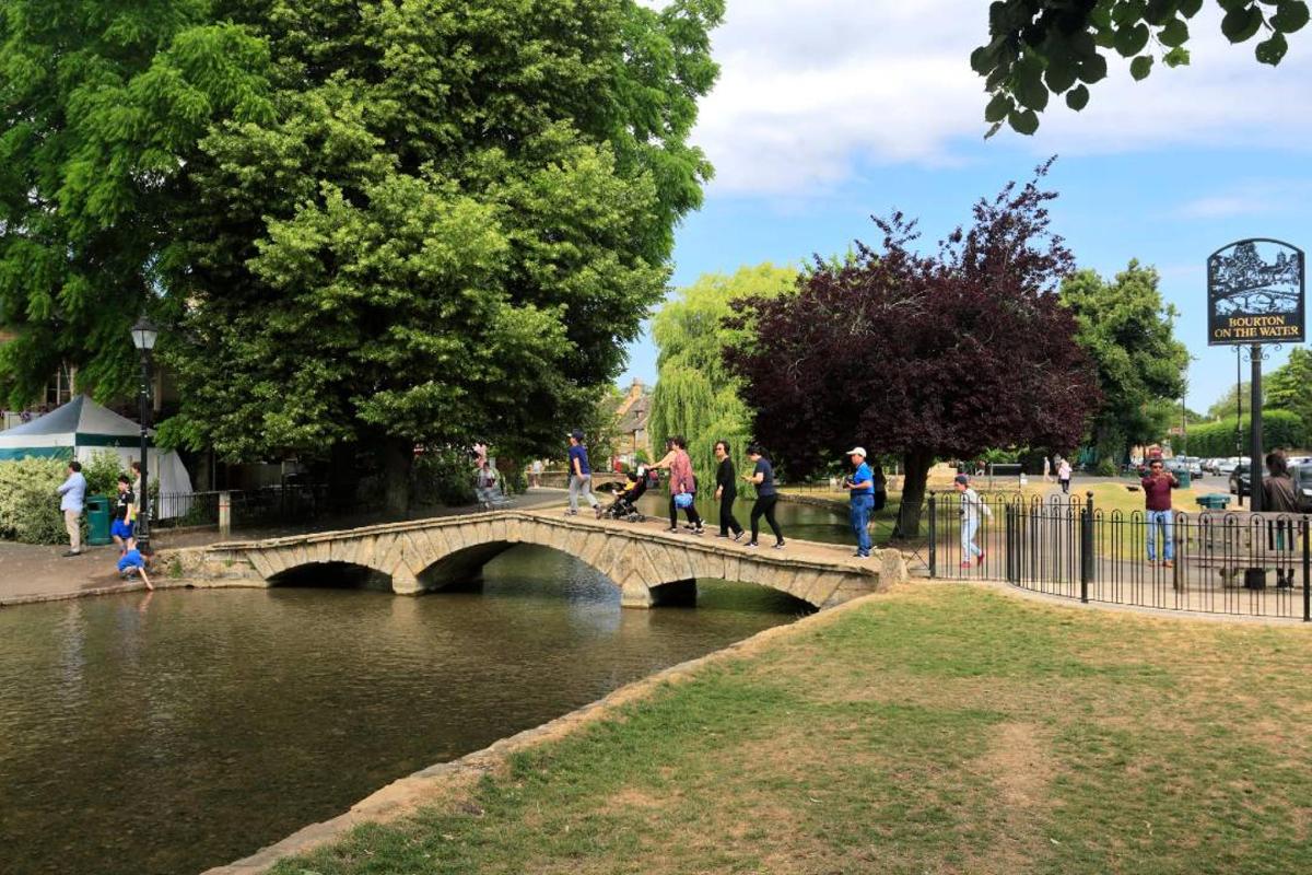 a group of people walking over a bridge over a river