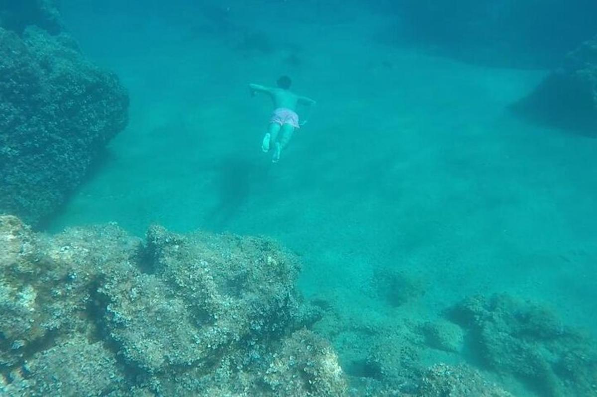 a man swimming in the ocean next to a reef