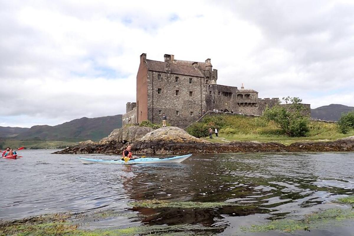 people kayaking on the river in front of a castle