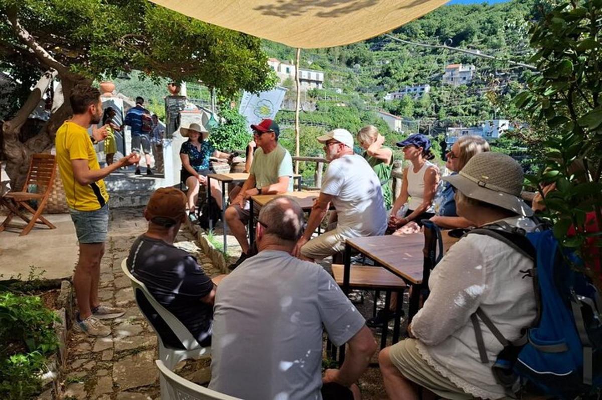 skupina ljudi, ki sedijo za mizami pod dežnikom