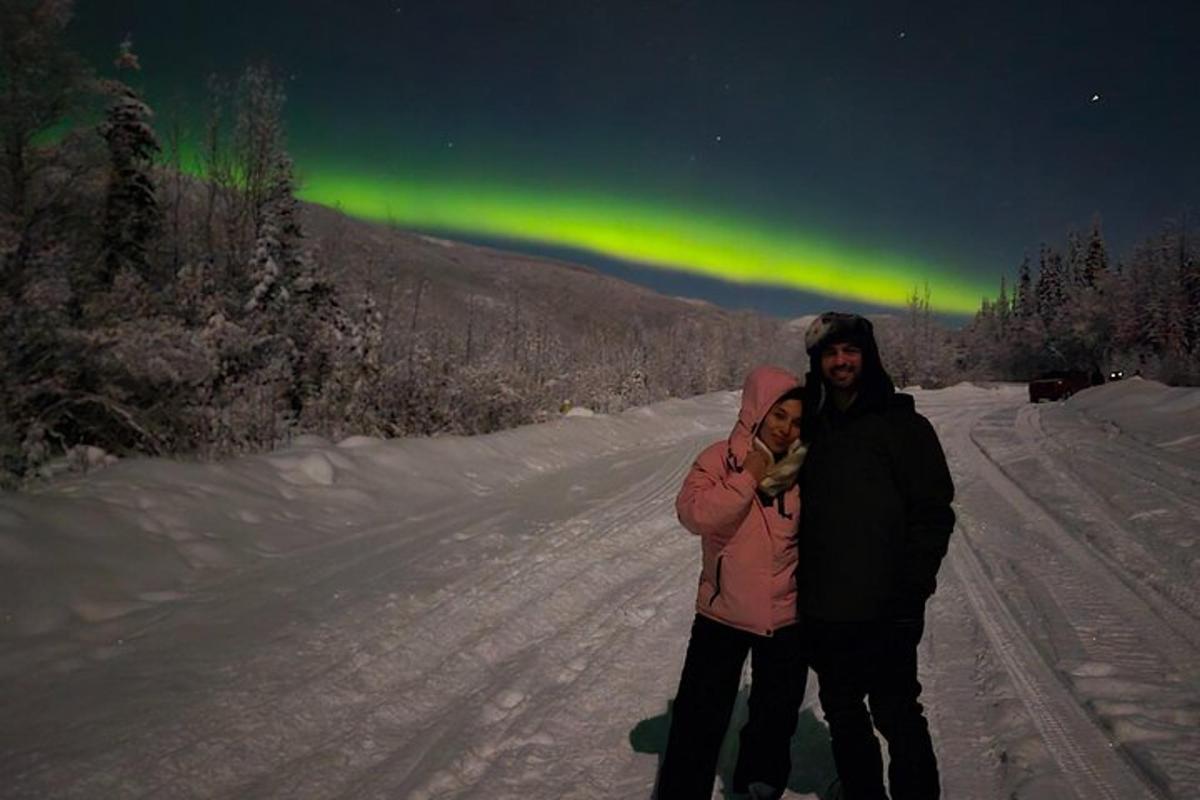 una dona que sosté un nadó davant de les aurores boreals