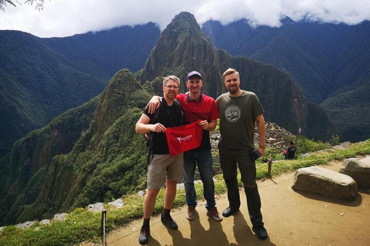 Un grupo de tres hombres de pie en la cima de una montaña.