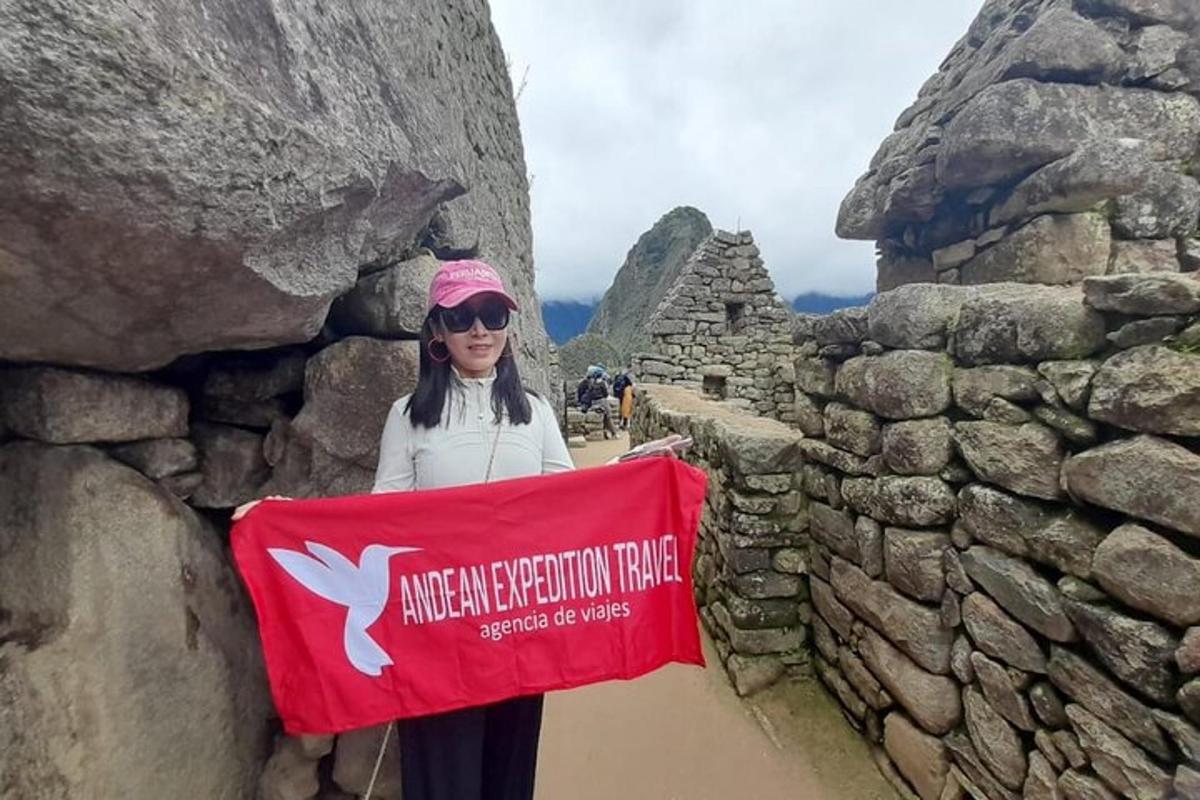 Una mujer parada junto a un muro de piedra sosteniendo una bandera