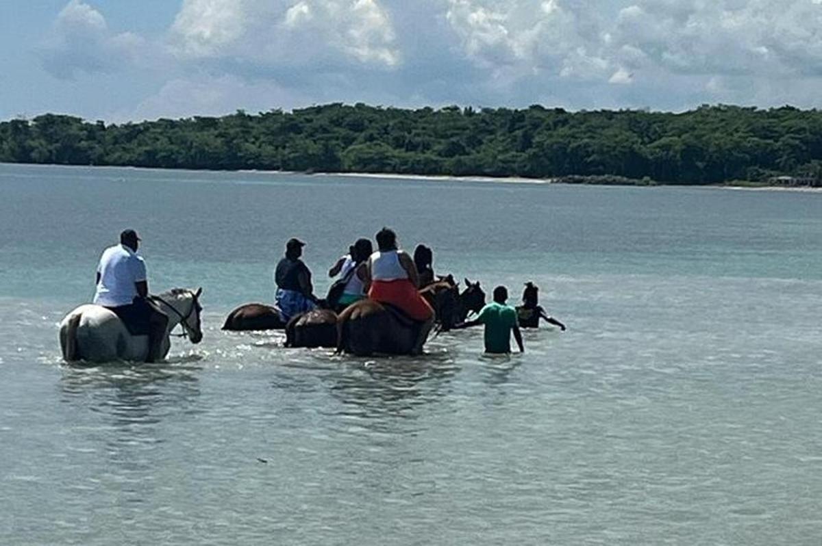 een groep mensen die op paarden in het water rijden