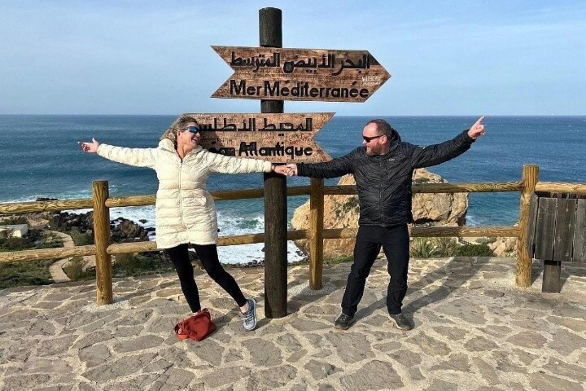 Egy férfi és egy nő áll egy tábla mellett a strandon