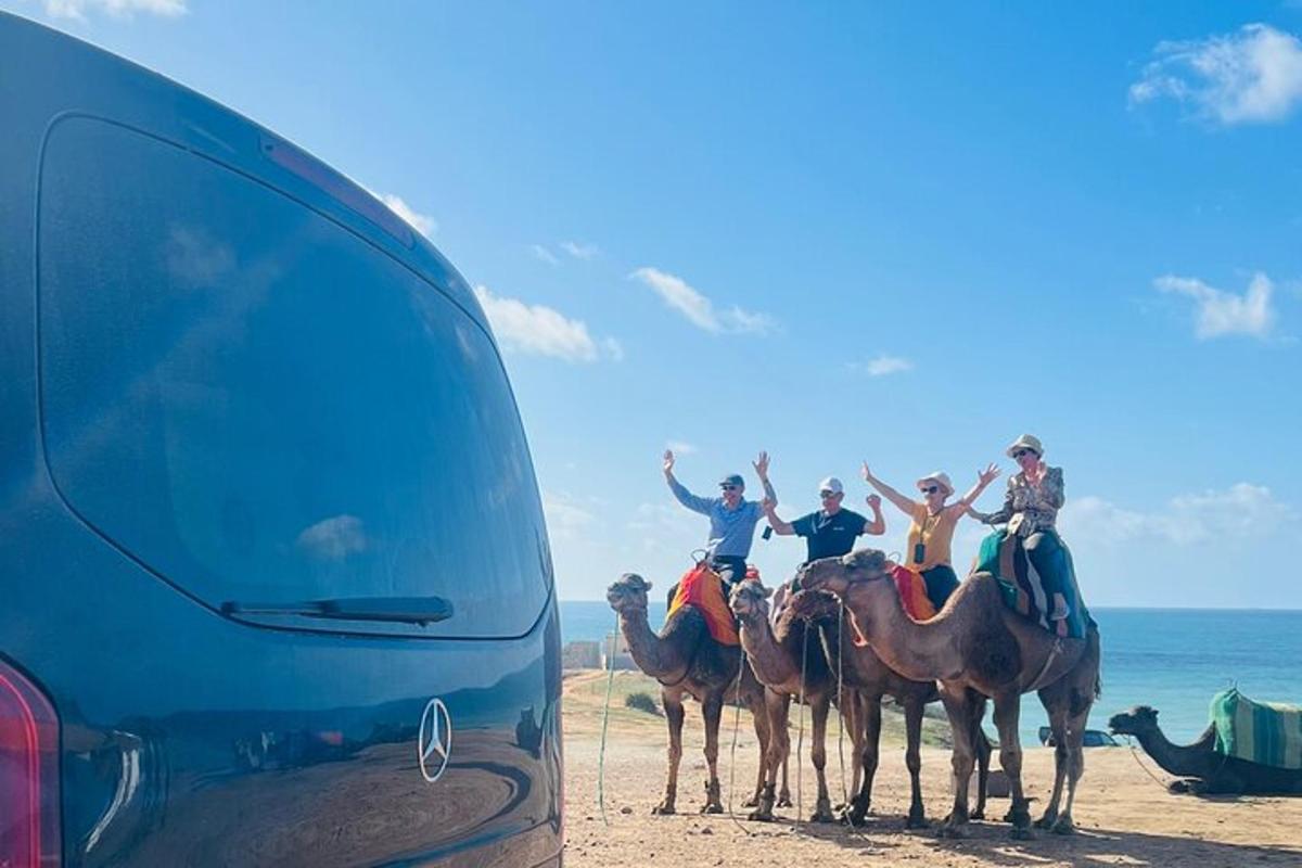 een groep mensen die op kamelen op het strand rijdt