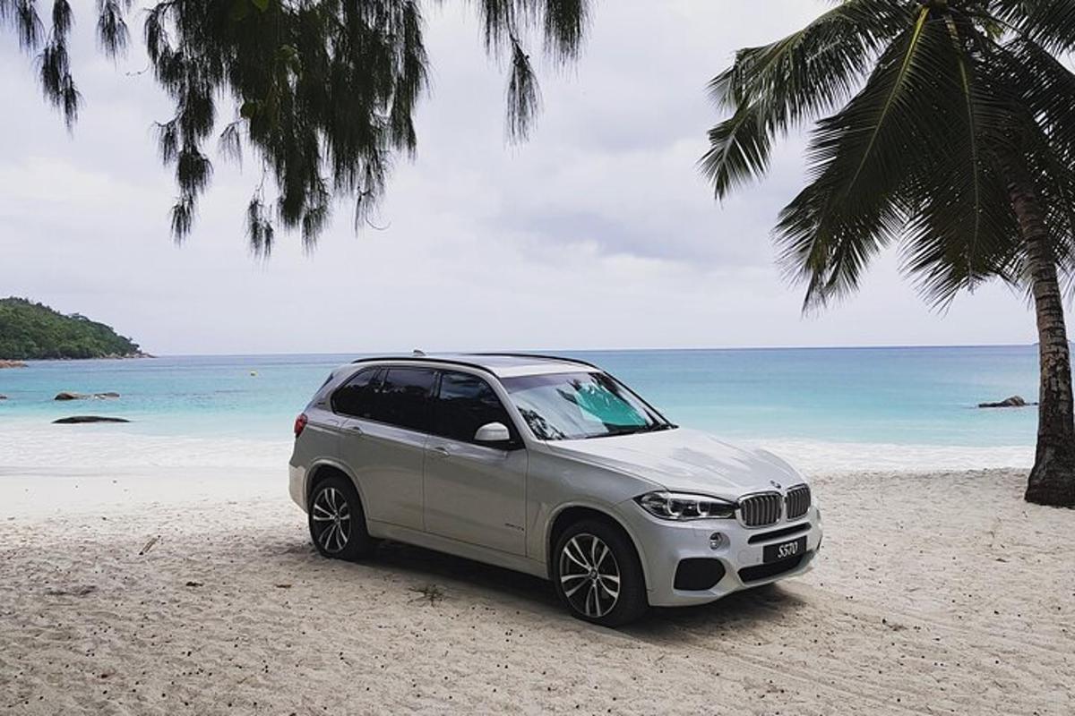 ein silbernes Auto, das an einem Strand in der Nähe des Ozeans geparkt ist