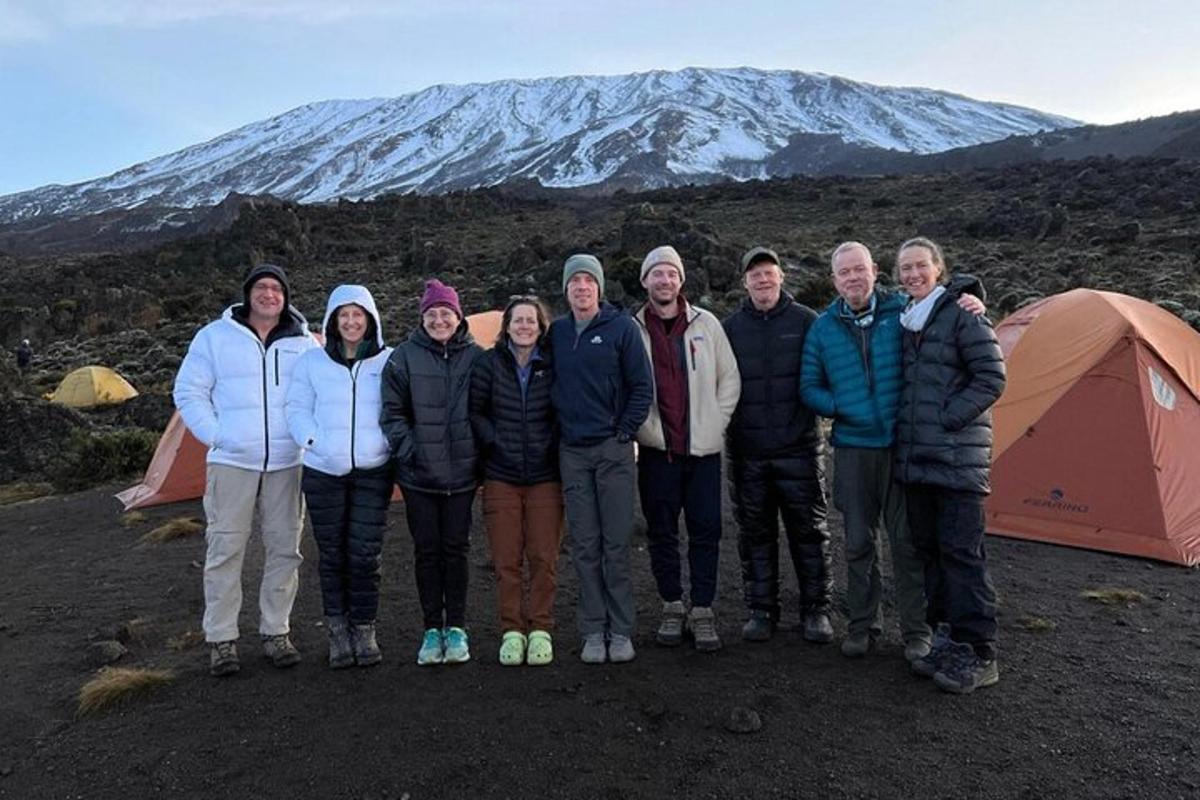 un gruppo di persone in piedi di fronte a una montagna coperta di neve