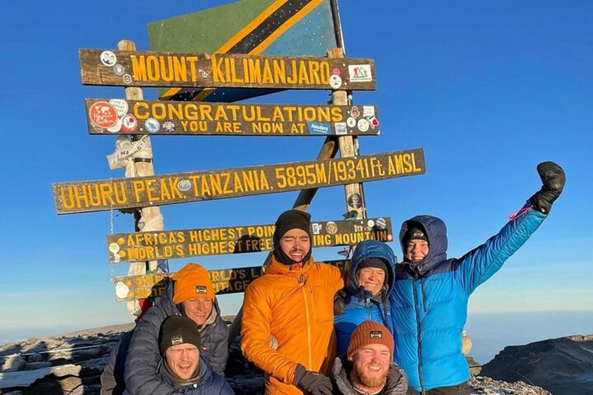 skupina lidí stojících před cedulí na hoře