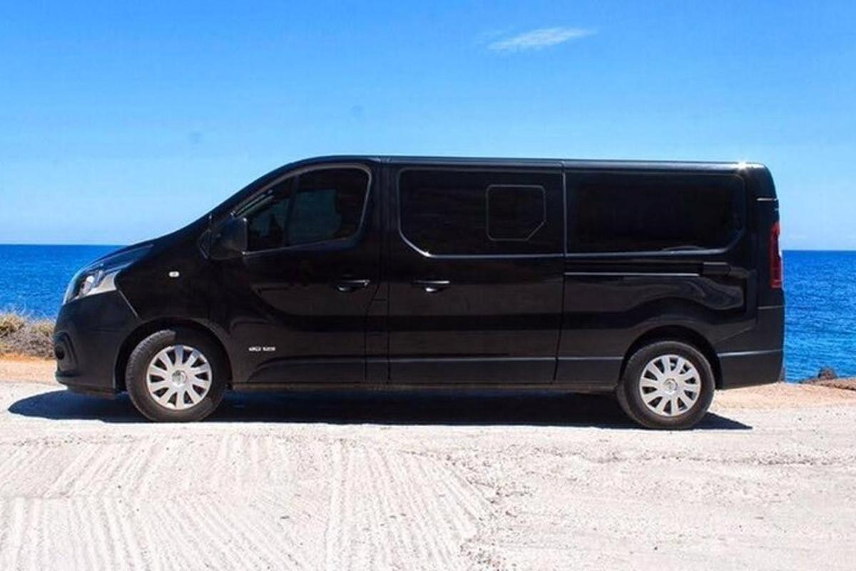 ein schwarzer Van, der am Strand neben dem Meer geparkt ist