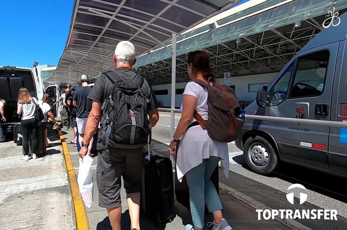 isang grupo ng mga tao na naghihintay sa isang airport kasama ang kanilang mga bagahe