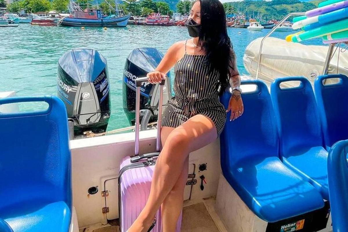 una donna in abito seduta su una barca con una valigia