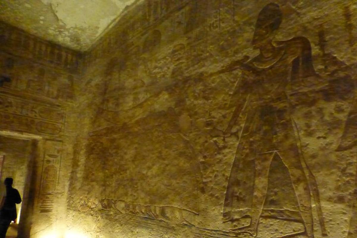 una persona che cammina davanti a un muro con un dipinto sopra