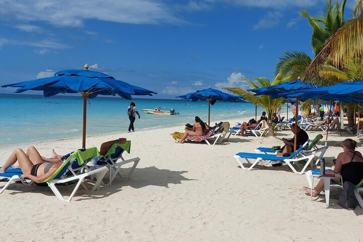 un gruppo di persone sedute su una spiaggia con ombrelloni blu
