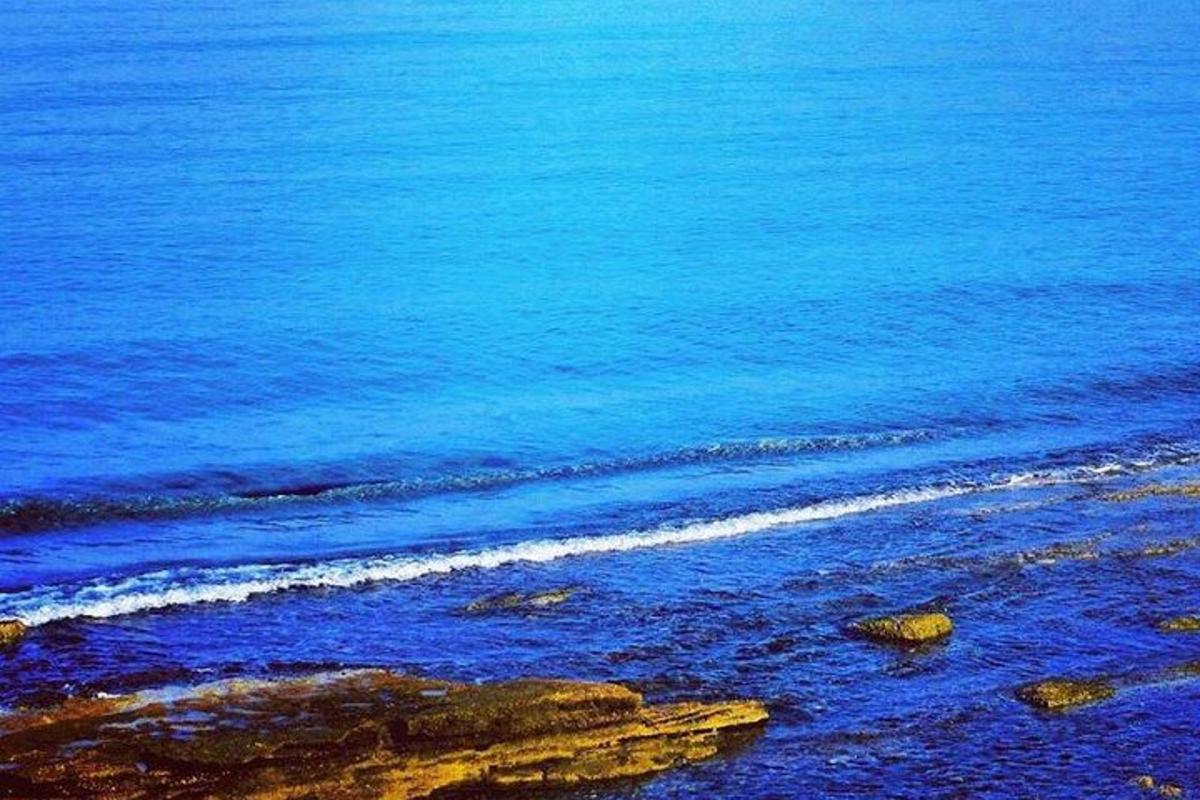 a view of a beach with blue water and rocks