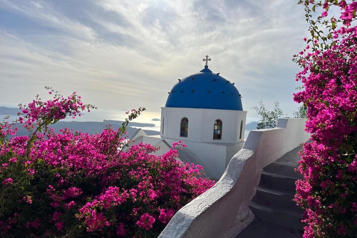 Una iglesia con una cúpula azul y flores rosas.