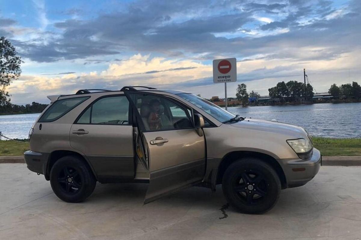 Un coche plateado estacionado junto a un cuerpo de agua.