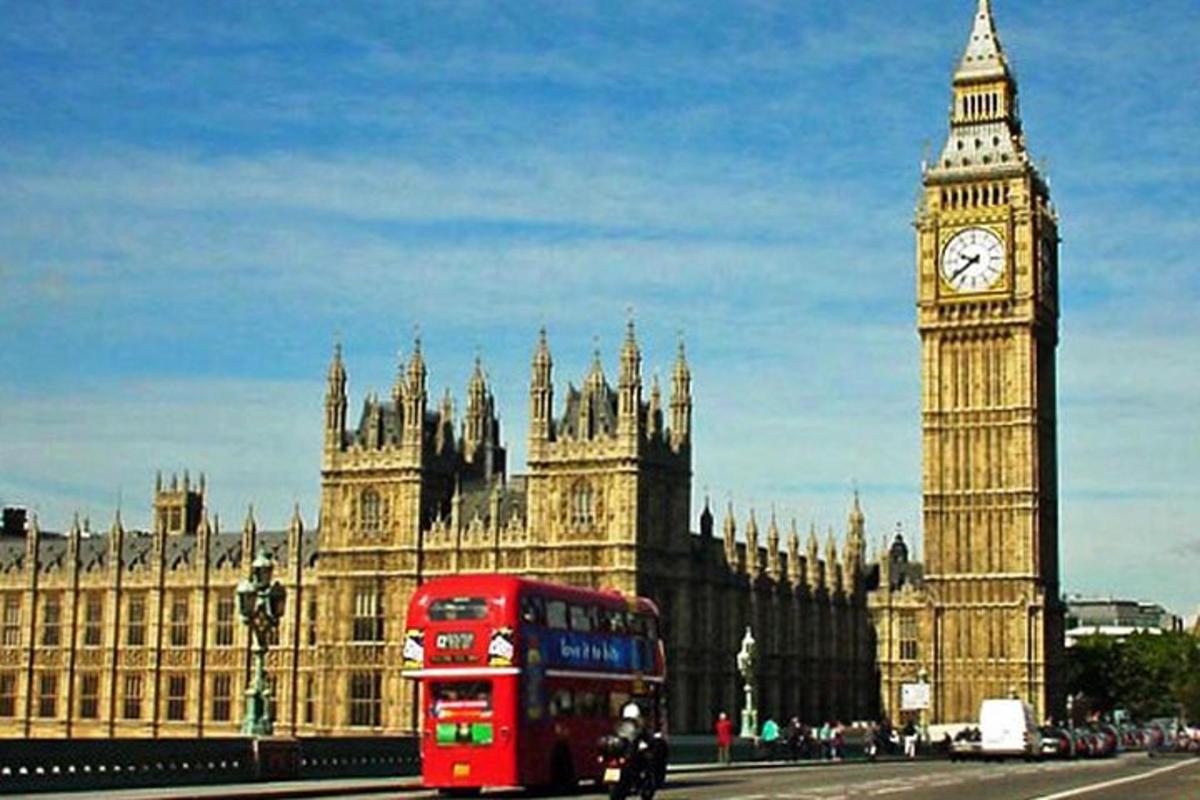 a red double decker bus driving past the big ben clock tower
