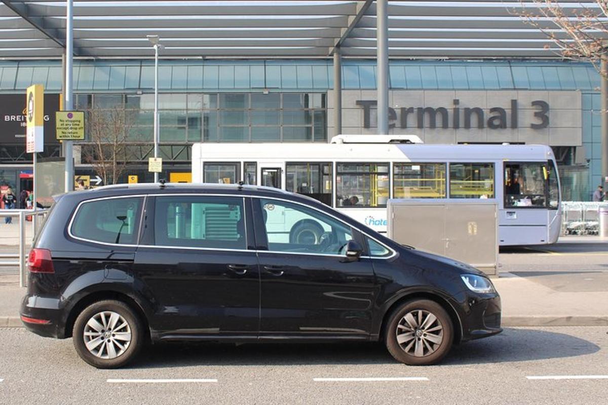 a black car parked in a parking lot with a bus