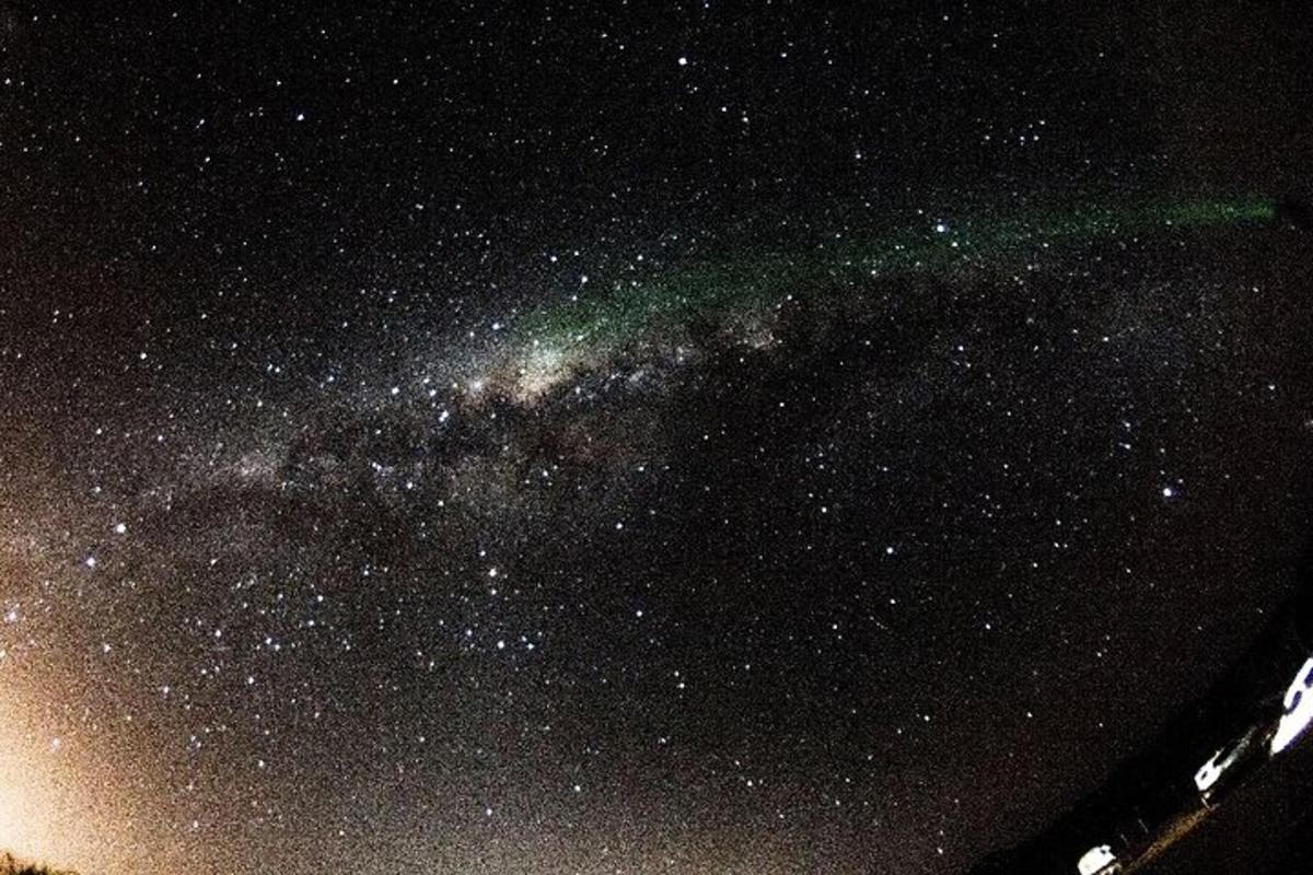 a starry night with a green streak in the sky