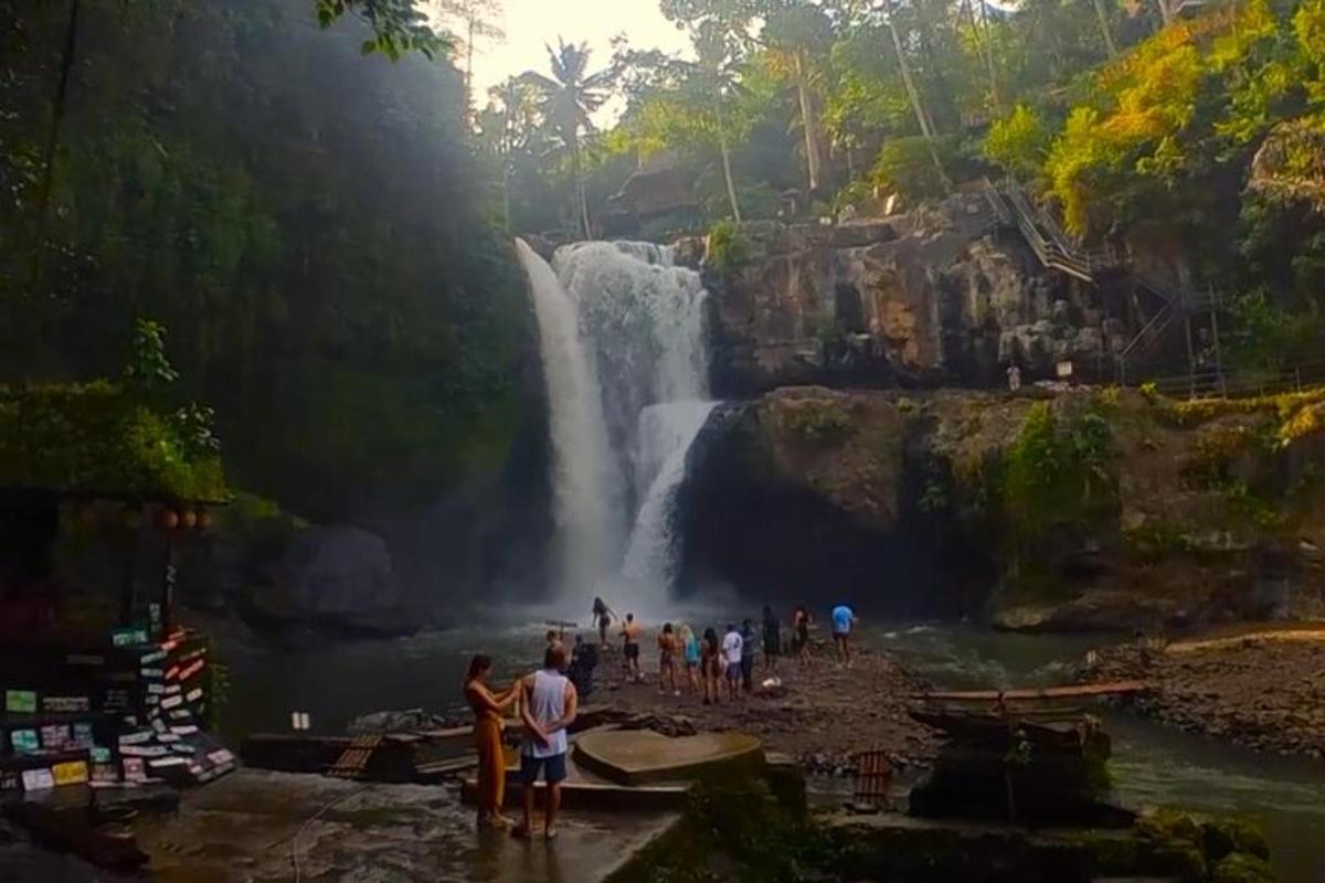 eine Gruppe von Menschen steht vor einem Wasserfall