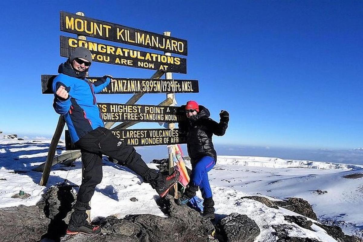 due persone in piedi accanto a un cartello su una montagna