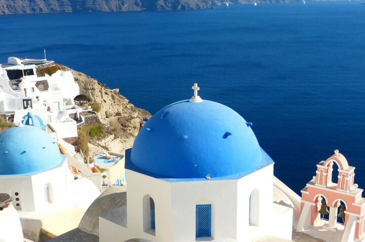 eine Gruppe weißer Kirchen mit blauen Kuppeln und dem Meer