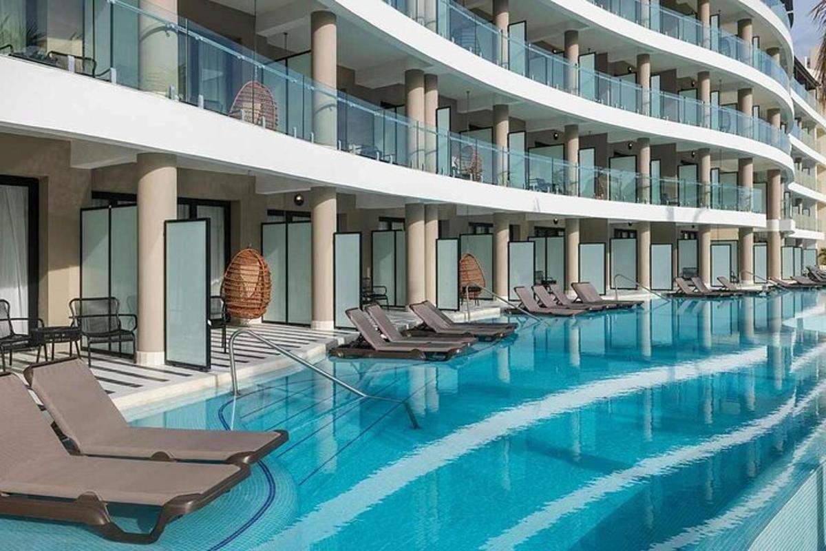 uma grande piscina com espreguiçadeiras em um prédio