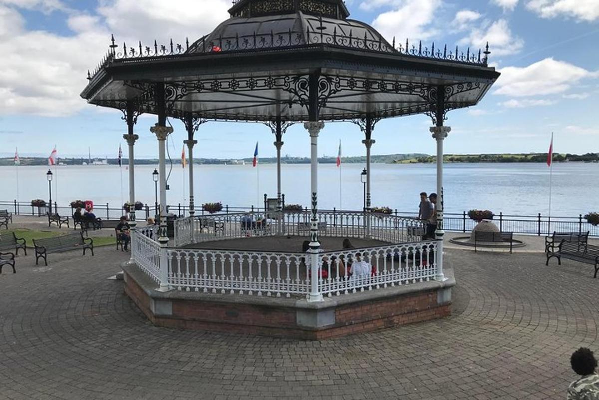 a gazebo with people sitting in it next to the water
