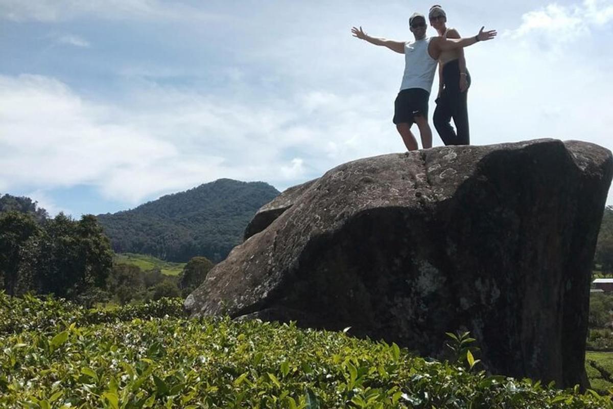 two people standing on top of a large rock