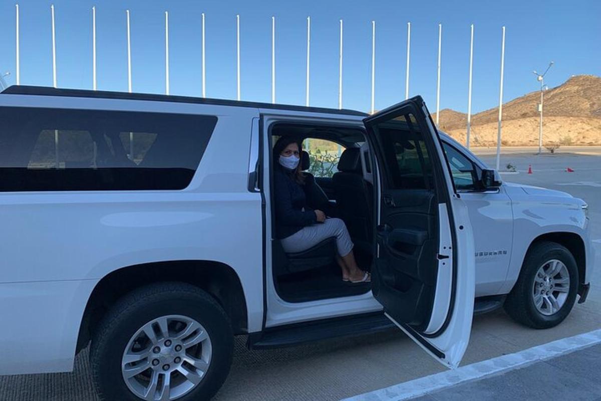 una donna che indossa una maschera seduta su una jeep bianca