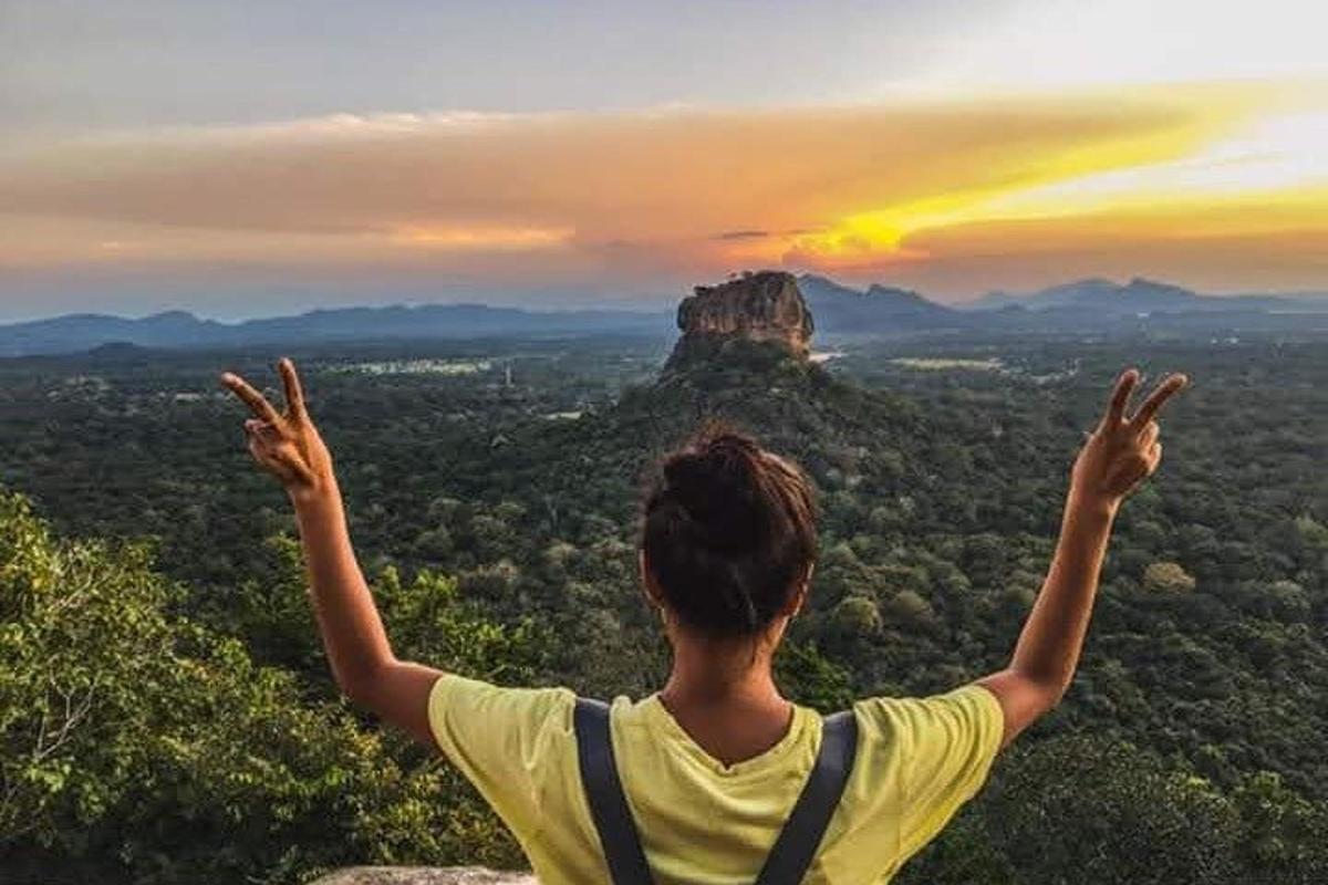 một người đàn ông đứng trên đỉnh núi với hai tay giơ lên