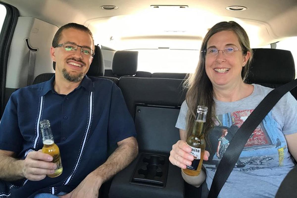 ein Mann und eine Frau sitzen in einem Auto und halten Bier