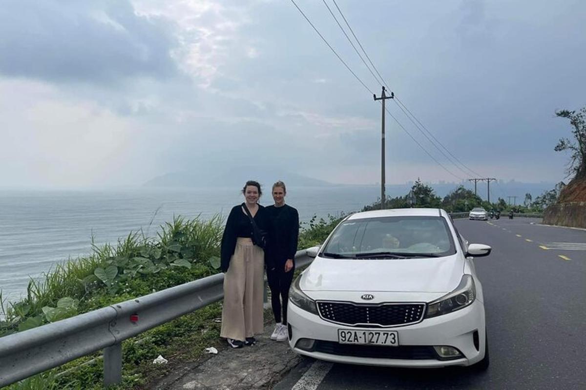 two women standing next to a white car on the side of a road