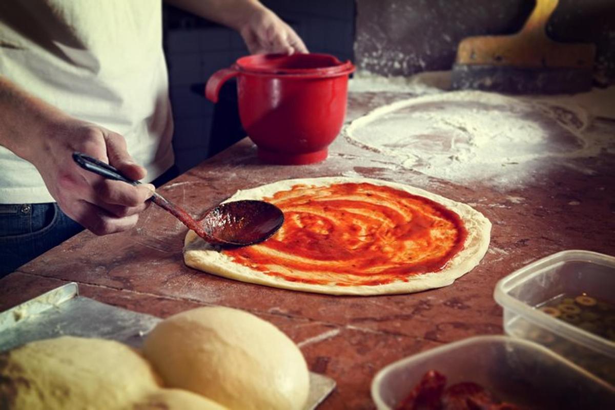 eine Person macht eine Pizza auf einem Tisch