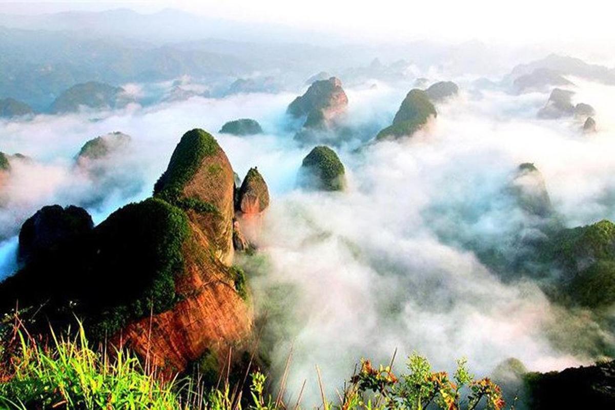 gunung berkabus dengan batu di latar depan