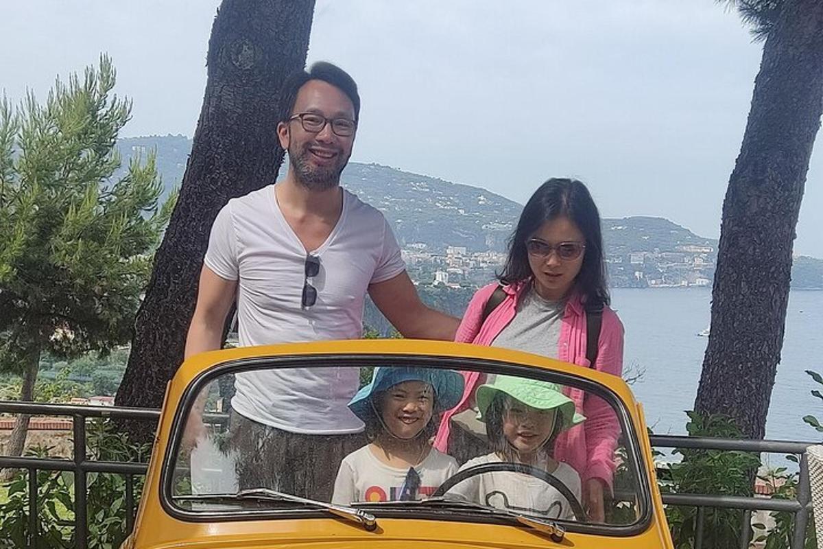 seorang pria dan dua wanita berdiri di samping mobil kuning