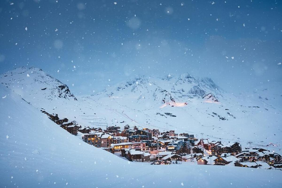 uma pequena cidade na neve em frente a uma montanha