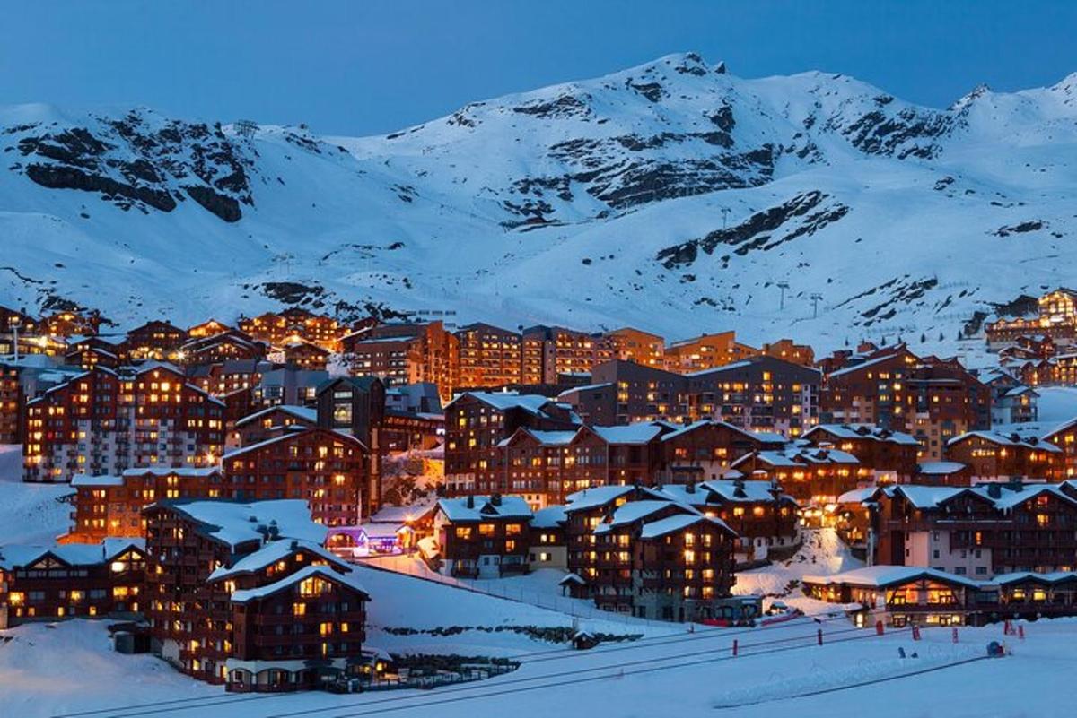 uma cidade na neve à noite com montanhas cobertas de neve