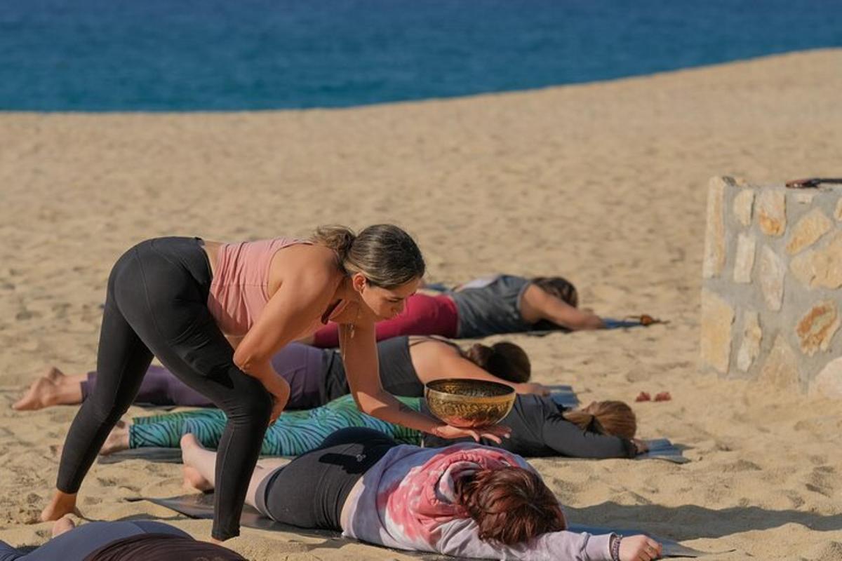 un grup de oameni care fac yoga pe plajă