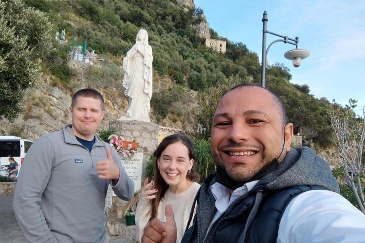 Tres personas haciendo un gesto de aprobación con el pulgar frente a una estatua