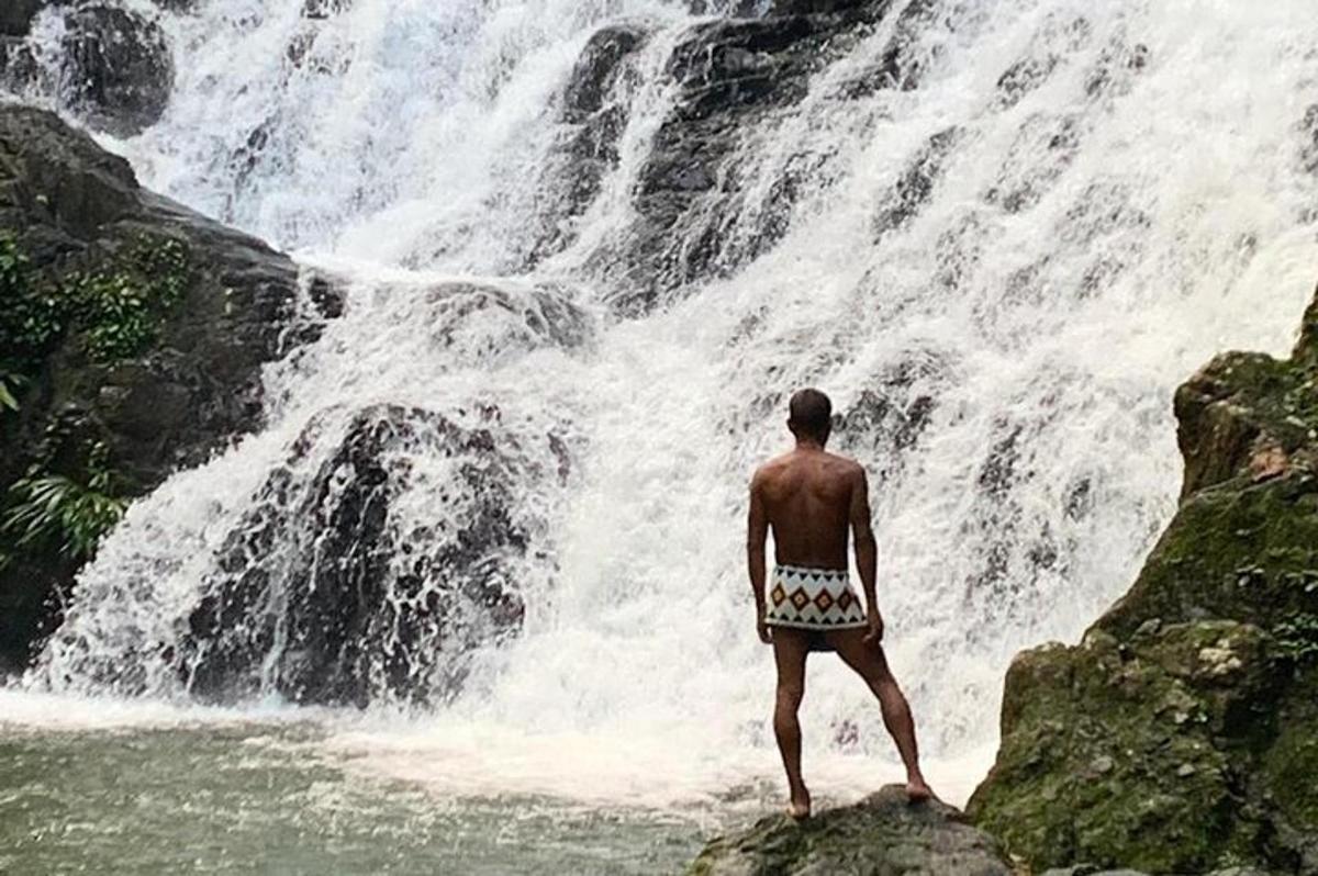 un uomo in piedi su una roccia di fronte a una cascata
