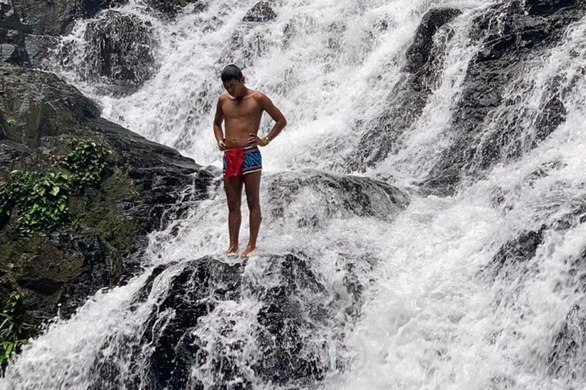 seorang lelaki berdiri di atas batu di hadapan air terjun