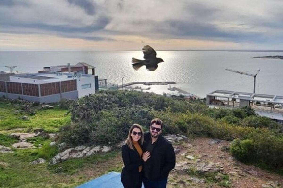 Ένας άντρας και μια γυναίκα στέκονται δίπλα στο νερό με ένα πουλί