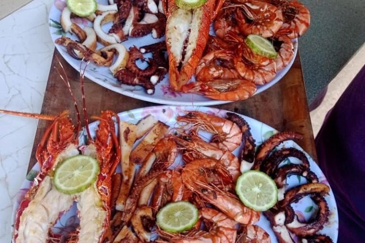 two plates of food with shrimp and limes on them