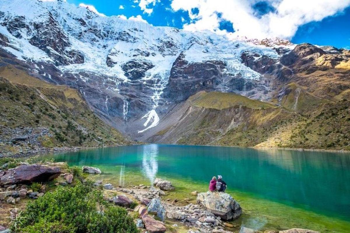 una persona parada sobre una roca cerca de un lago de montaña