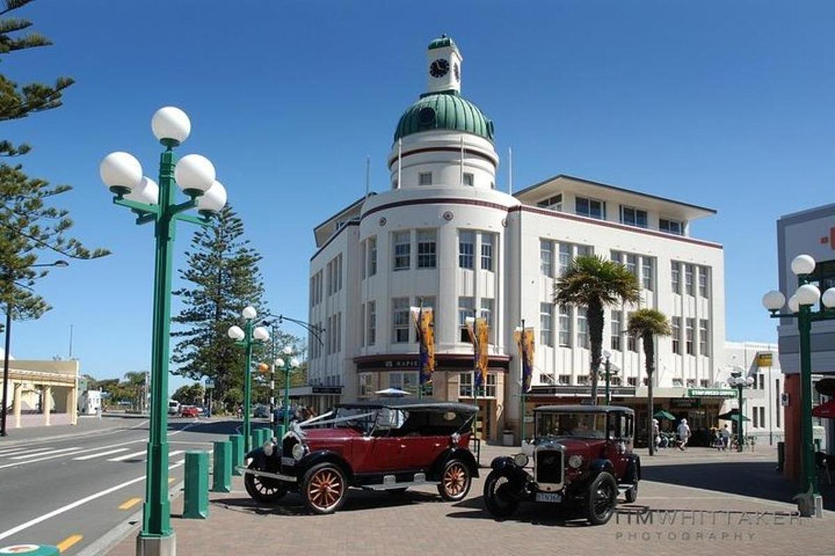 two old cars parked in front of a building with a lighthouse