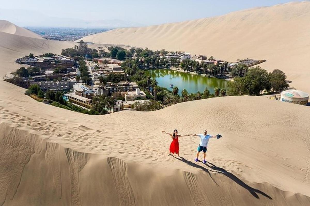 Un hombre y una mujer de pie en una duna de arena en el desierto